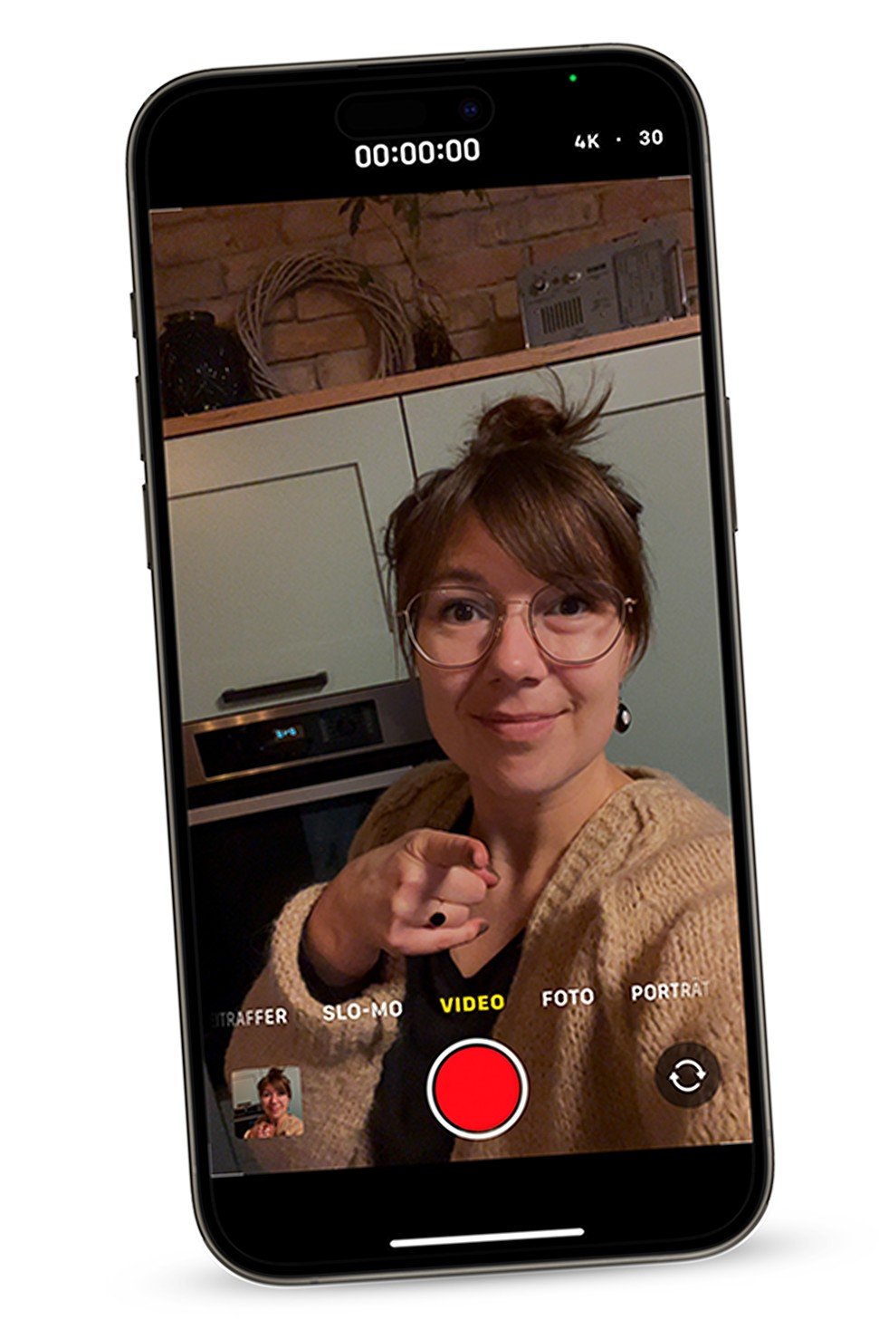 image of a smartphone which captures a woman smiling and pointing into the camera 